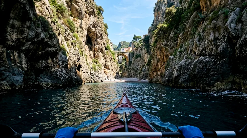 Kayak approaching the Fiordo di Furore fjord entrance between tall cliffs.