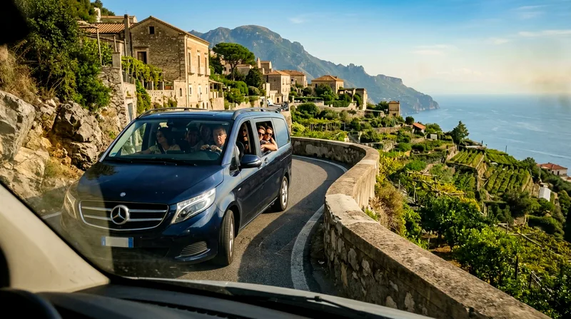 Small minivan with passengers climbing winding mountain road toward Ravello.